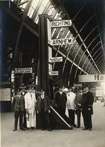 881800 Afbeelding van spoorwegpersoneel bij een richtingaanwijzer met bestemmingen voor Arnhem en Utrecht over ...